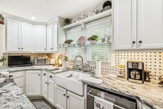 kitchen featuring white cabinets, stainless steel dishwasher, sink, and light stone counters