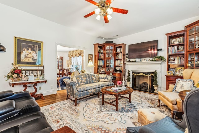 living area featuring a fireplace, wood finished floors, and a ceiling fan