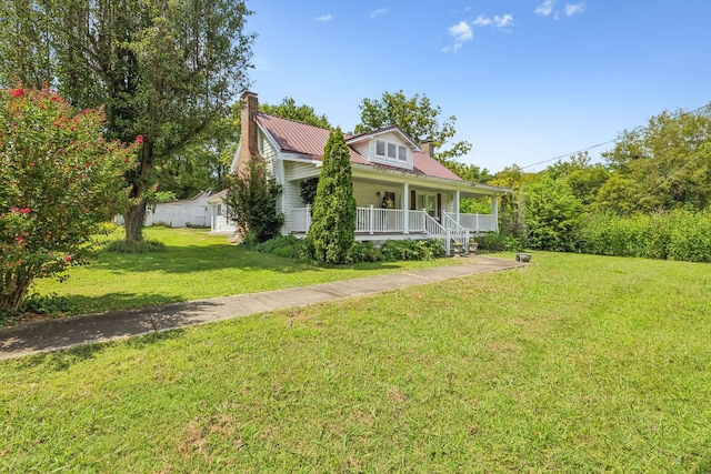 view of front of home featuring covered porch, metal roof, a front lawn, and a chimney