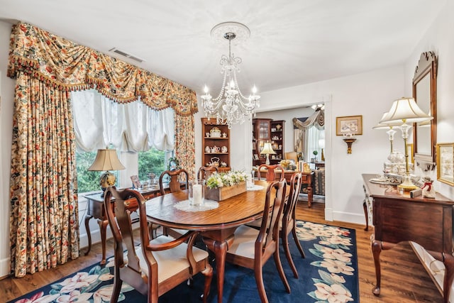 dining room featuring baseboards, visible vents, an inviting chandelier, and wood finished floors