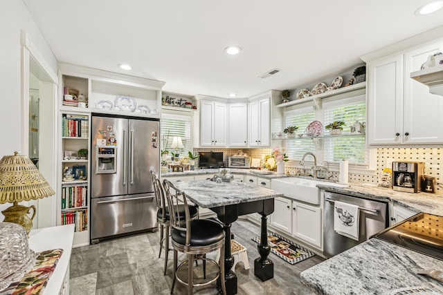 kitchen with appliances with stainless steel finishes, a healthy amount of sunlight, white cabinetry, and backsplash