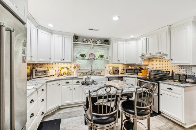 kitchen with light tile patterned flooring, decorative backsplash, light stone counters, a breakfast bar area, and stainless steel appliances