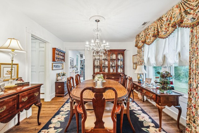 dining space with light wood-type flooring and an inviting chandelier