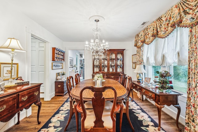 dining space with light wood-style floors, visible vents, and an inviting chandelier