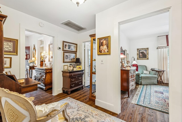 sitting room with baseboards, visible vents, and dark wood finished floors