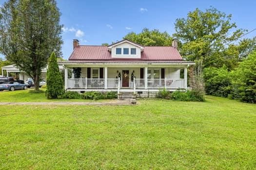 view of front of property featuring covered porch, a chimney, and a front lawn