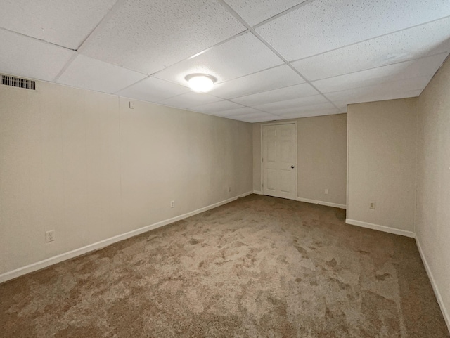 finished below grade area featuring visible vents, carpet, a paneled ceiling, and baseboards