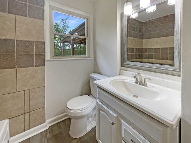 full bathroom with a tile shower, vanity, toilet, and wood finished floors