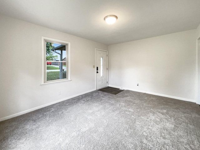 empty room featuring dark carpet and baseboards