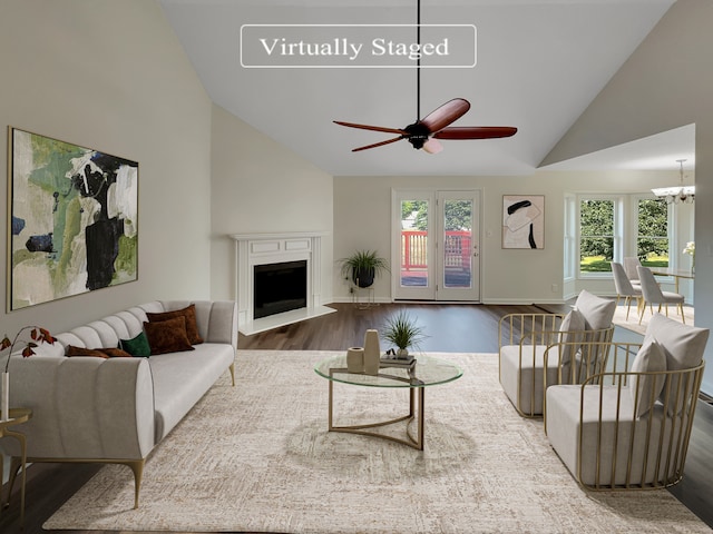 living room with ceiling fan with notable chandelier, high vaulted ceiling, and wood-type flooring