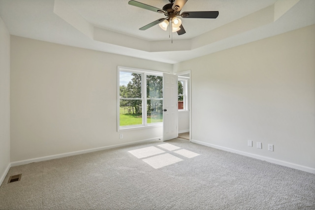 carpeted spare room featuring ceiling fan and a raised ceiling