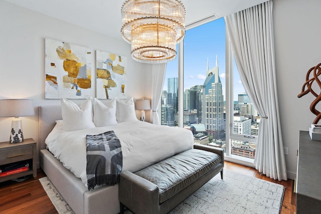 bedroom with hardwood / wood-style flooring, an inviting chandelier, access to exterior, and a wall of windows