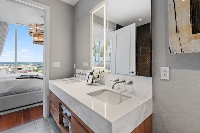 bathroom featuring a notable chandelier, dual bowl vanity, and tile patterned floors