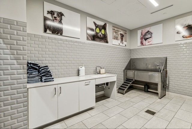 interior space featuring white cabinets, sink, and light tile patterned flooring