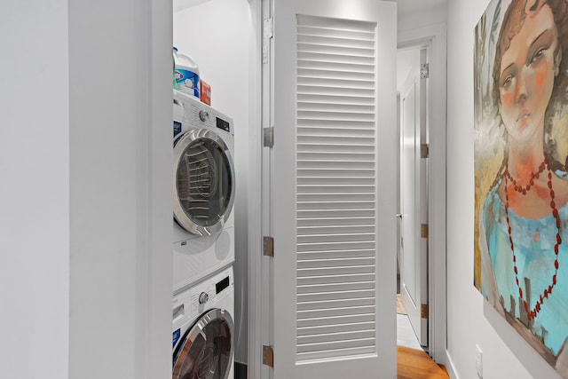 clothes washing area featuring stacked washer and dryer and light wood-type flooring