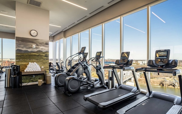 gym with dark tile patterned flooring and a water view