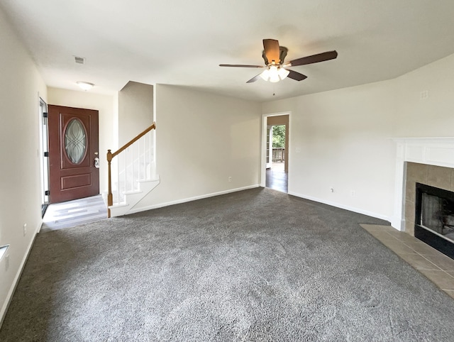 unfurnished living room featuring ceiling fan, carpet floors, and a tile fireplace