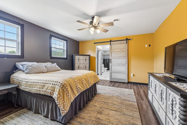 bedroom with ceiling fan, hardwood / wood-style flooring, and a barn door