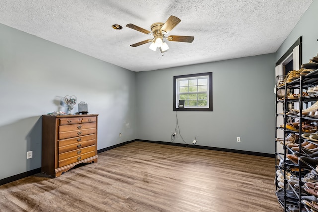 interior space with a textured ceiling, ceiling fan, and hardwood / wood-style floors