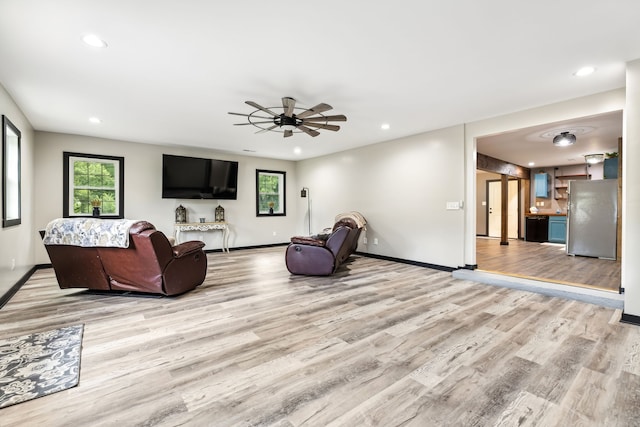 living room with ceiling fan and light hardwood / wood-style flooring