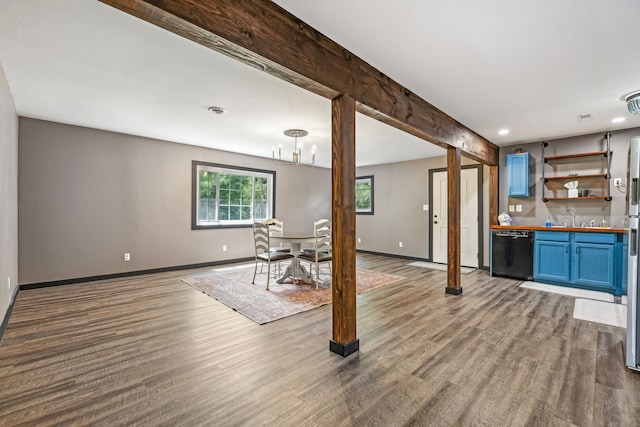 unfurnished living room featuring beam ceiling, sink, and wood-type flooring