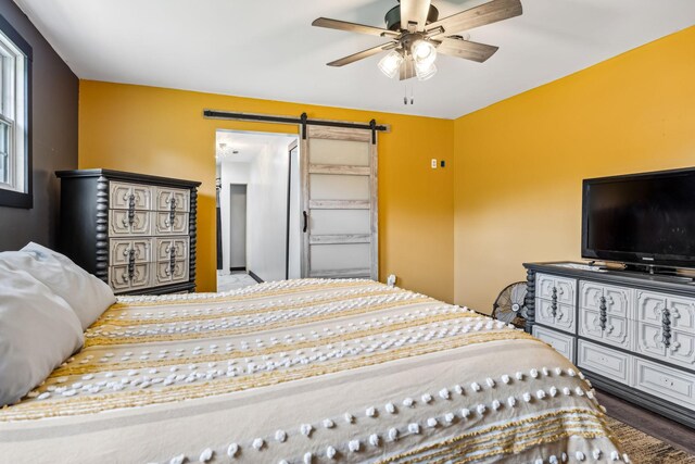 bedroom featuring ceiling fan, a barn door, and hardwood / wood-style floors