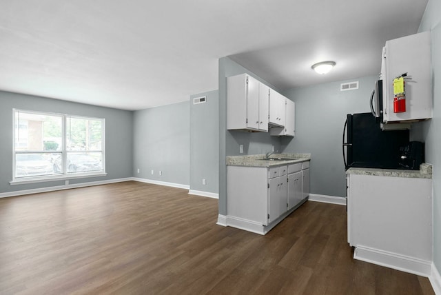 kitchen with black refrigerator, dark wood-type flooring, and white cabinets