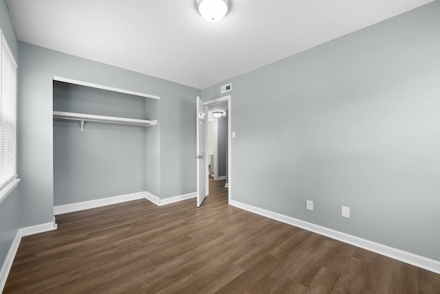 unfurnished bedroom with a closet and dark hardwood / wood-style floors