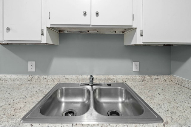 interior space featuring sink, light stone counters, and white cabinets