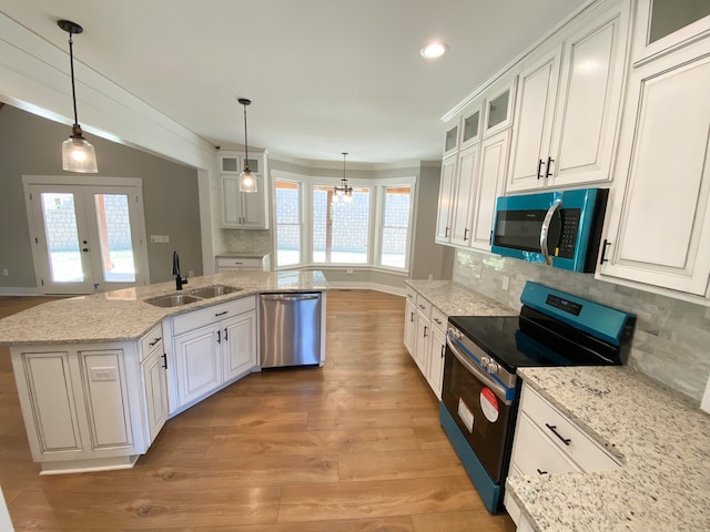 kitchen featuring backsplash, stainless steel appliances, light hardwood / wood-style flooring, and decorative light fixtures