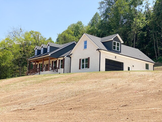 view of side of property featuring covered porch and a garage