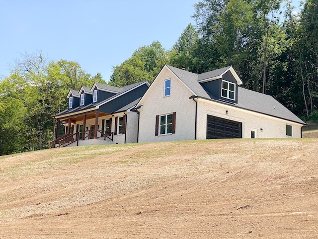 view of home's exterior featuring a garage, brick siding, a porch, and a yard