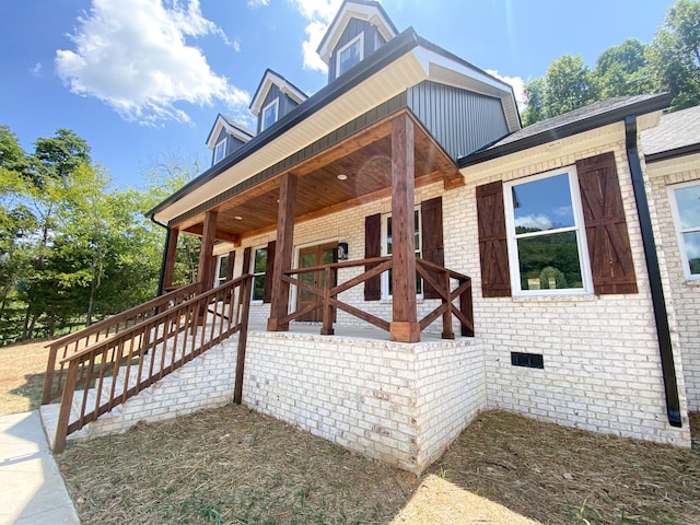 view of front of property featuring covered porch, brick siding, and crawl space