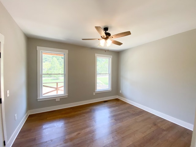 unfurnished room with ceiling fan, dark wood finished floors, and baseboards