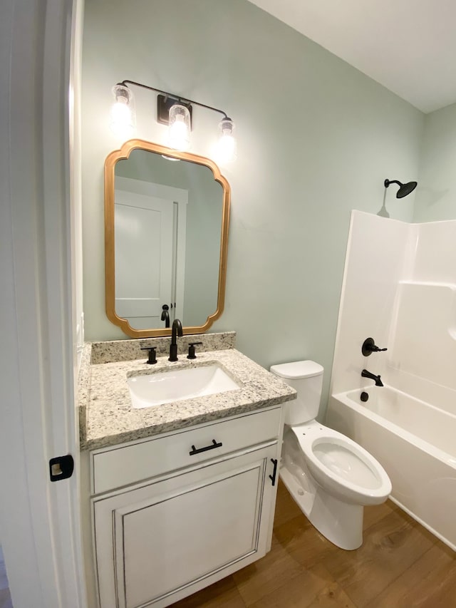 bathroom with toilet, shower / tub combination, wood finished floors, and vanity