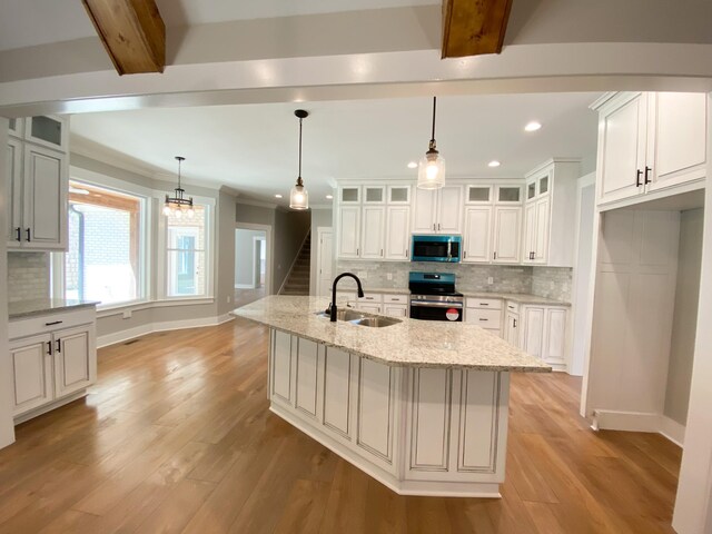 kitchen with light wood-type flooring, tasteful backsplash, beam ceiling, appliances with stainless steel finishes, and sink