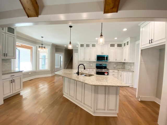 kitchen featuring electric stove, an island with sink, glass insert cabinets, light stone counters, and a sink