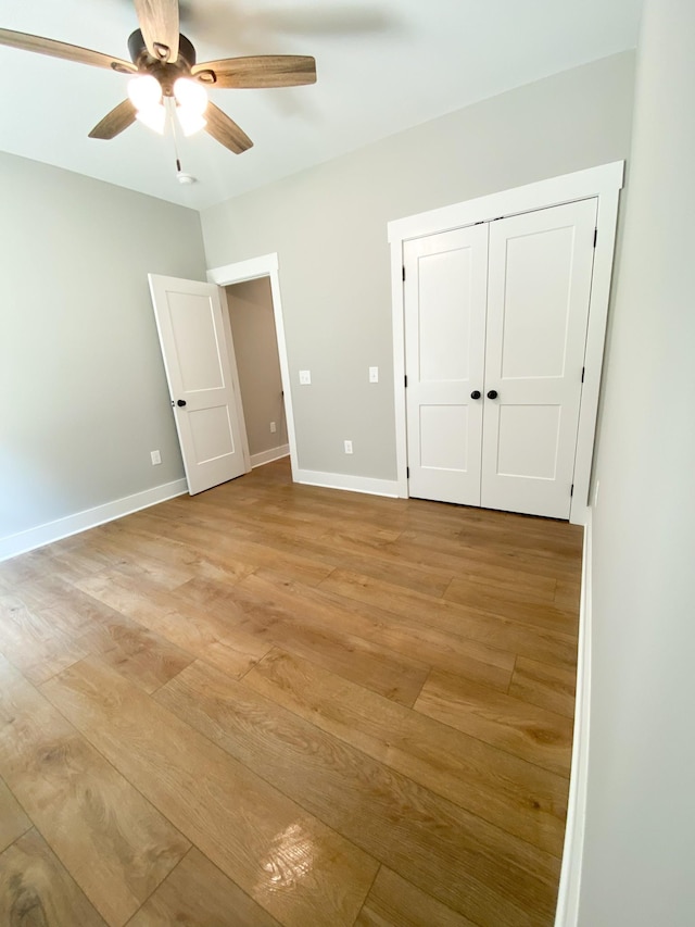 unfurnished bedroom with a ceiling fan, a closet, light wood-style flooring, and baseboards