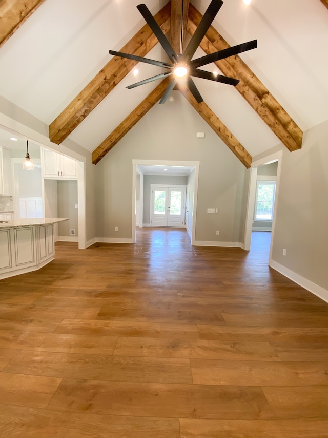 additional living space featuring high vaulted ceiling, beam ceiling, light hardwood / wood-style flooring, and french doors