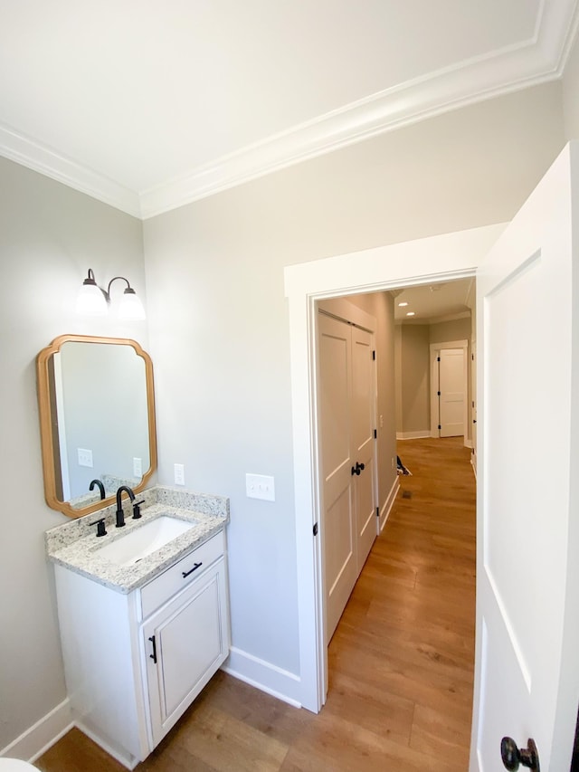 bathroom with baseboards, ornamental molding, wood finished floors, and vanity