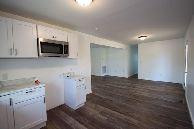 kitchen featuring visible vents, white cabinetry, baseboards, dark wood-style floors, and stainless steel microwave