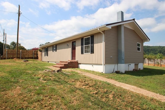 view of front facade featuring a chimney, entry steps, crawl space, fence, and a front lawn