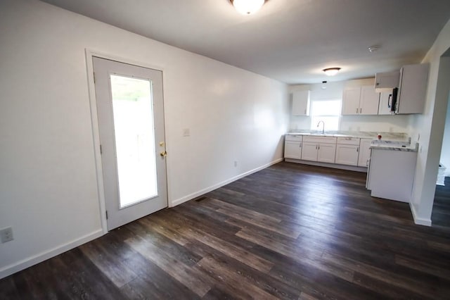 kitchen with dark wood-style floors, baseboards, white cabinetry, and light countertops