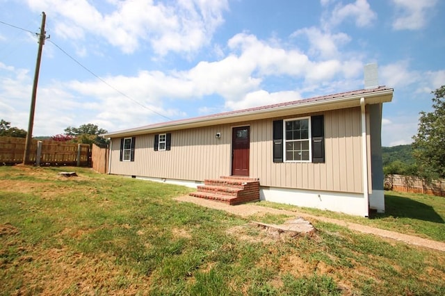 view of front of home with entry steps, crawl space, fence, and a front lawn