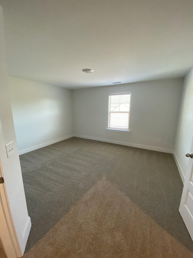 spare room featuring dark colored carpet