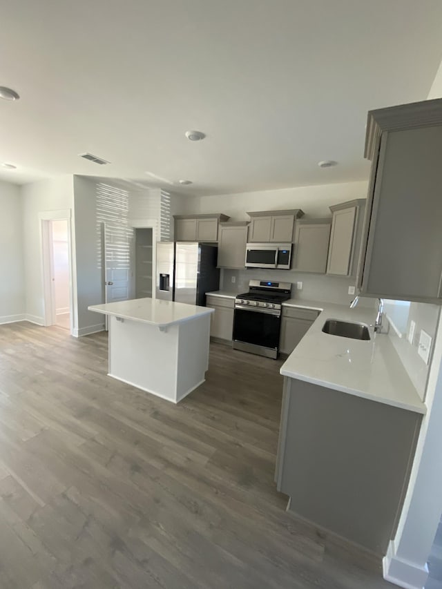 7643 Rookers Bend Dr, Smyrna, TN 37167 - kitchen with stainless steel appliances, gray cabinetry, a kitchen island, wood finished floors, and light countertops
