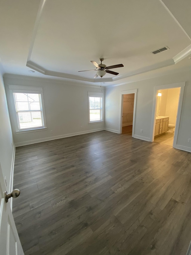 unfurnished bedroom with a walk in closet, ceiling fan, dark wood-type flooring, and multiple windows