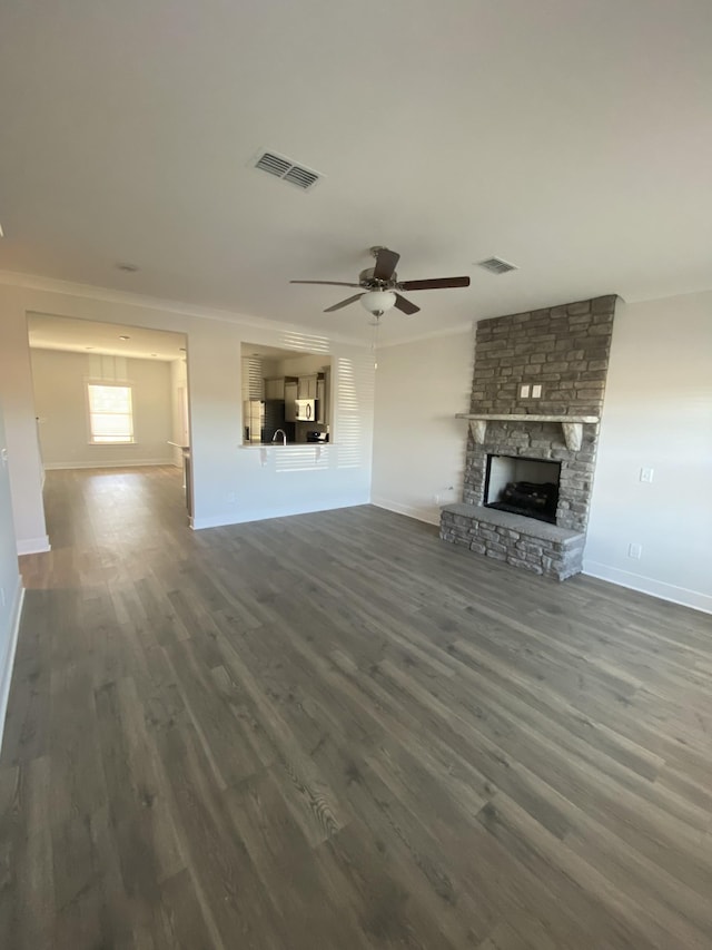 unfurnished living room with a fireplace, dark hardwood / wood-style floors, ceiling fan, and crown molding