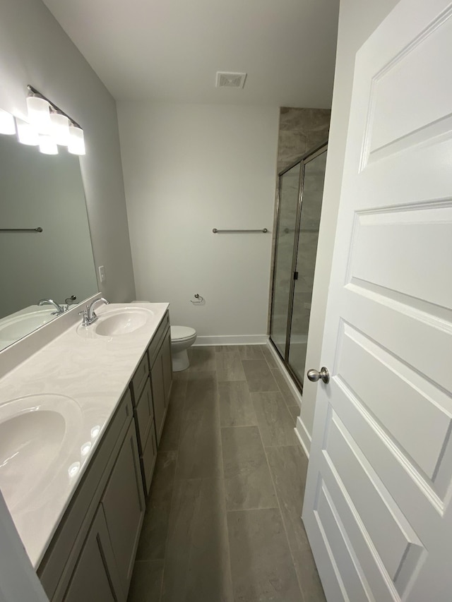 bathroom featuring vanity, toilet, and a shower with door