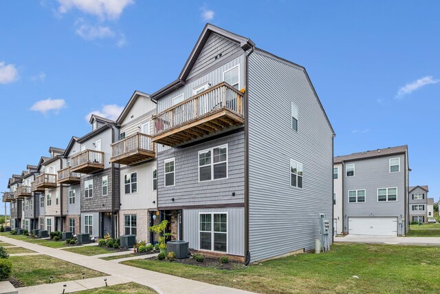 exterior space featuring a garage, central air condition unit, a balcony, and a front yard